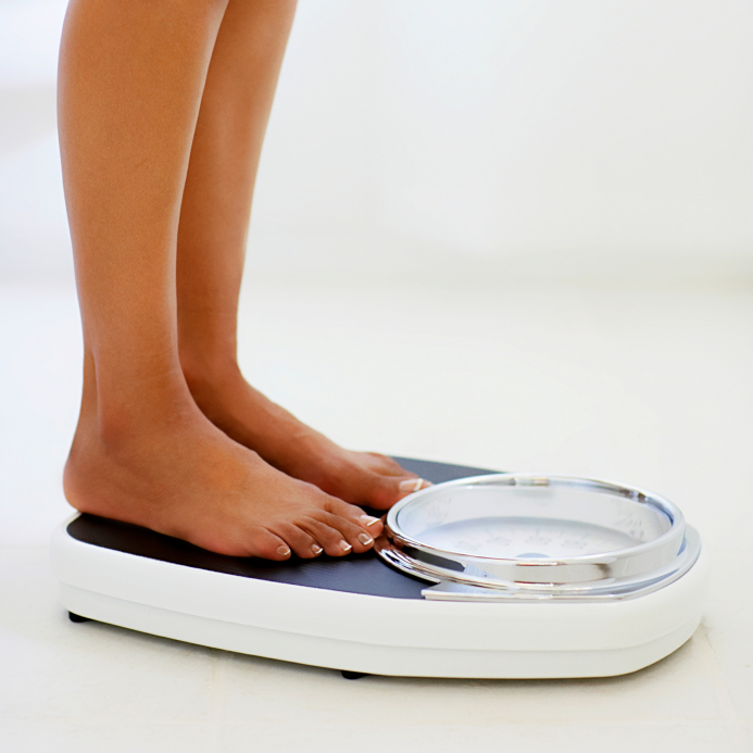 Woman weighing herself on the bathroom scale.